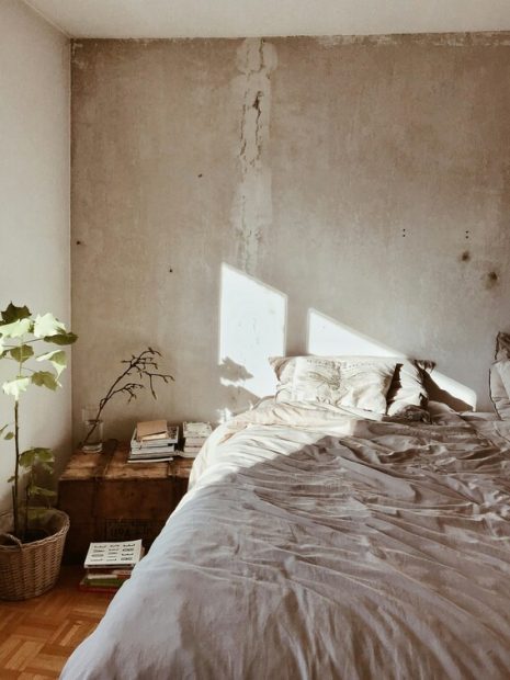 appartement lumineux avec lit aux couleurs beiges et mur en béton